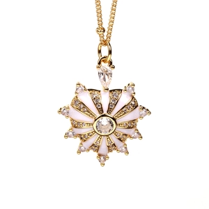 Dettaglio della collana con ciondolo a sole dorato con smalto bianco e zirconi lucidi