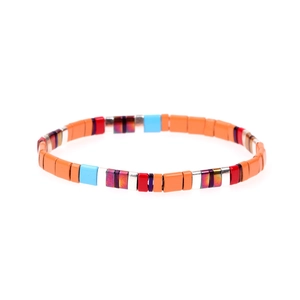 Dettaglio di perline Tila colorate in smalto su cordino elastico con accenti metallici lucidi