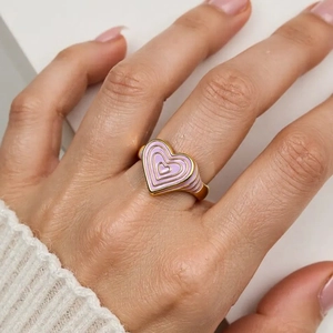 Bague cœur en émail rose avec base dorée portée par un mannequin pour un look chic