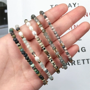 Hand met een vijfdelige set kralenarmbanden met zoetwaterparels en halfedelstenen