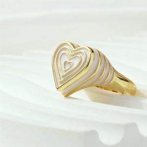 Vue latérale macro d'une bague coeur avec émail blanc et détails plaqués or
