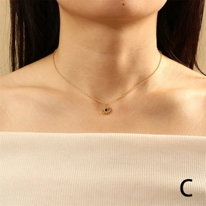 Detail of gold evil eye necklace with blue zircon and eyelash design on neck