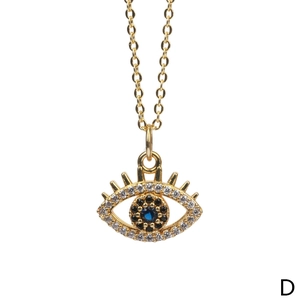 Detail shot of golden Evil Eye pendant with blue stone and zircon inlay on a delicate chain