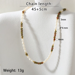 Detail of beaded necklace with freshwater pearls, green stones and gold accents on a mannequin