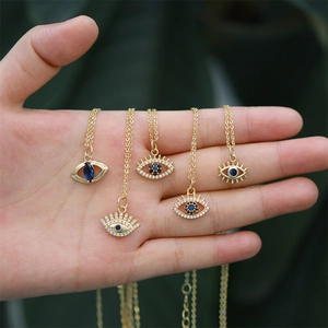 Close-up of five assorted gold-plated Turkish evil eye necklaces held in hand