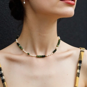 Vintage pearl necklace with green stone beads and gold accents on a model neck