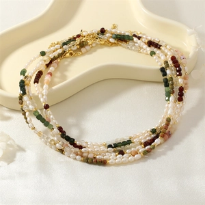 Vintage pearl necklace with green opal and multi-colored stones on a cream tray
