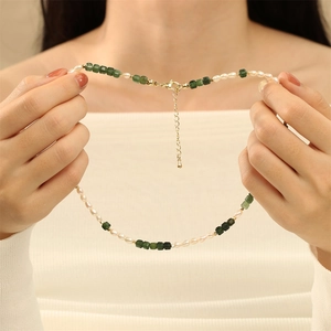 Detail of freshwater pearls and green square beads on a necklace with golden lobster clasp