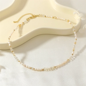 Close-up of pearl necklace with green gemstones and golden beads on an elegant plate