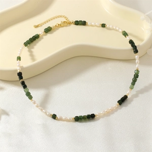 Detailed shot of pearl and green stone necklace on an elegant white display stand