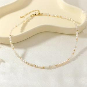 Detail of freshwater pearl necklace with translucent stones and gold beads on ceramic