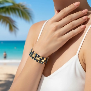 Detail of bohemian gold-plated cuff bracelet featuring deep blue glitter resin inlays
