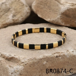 Detail of black and gold Tila tile bead stretch bracelet on a natural stone surface