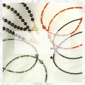 Detail of colorful stone beads necklaces with evil eye pendants on white silk fabric