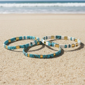 Bohemian colorful enamel tile bracelets set on beach sand with sea background