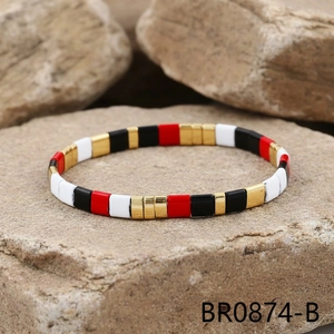 Detail of colorful Tila bead bracelet with red, black, and white glaze on natural stone