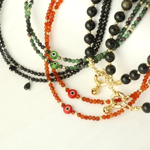Close-up of semi-precious stone beaded necklaces with evil eye charms and gold clasps