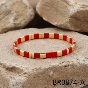 Detail shot of red and gold tile beads bracelet on a natural textured rock background