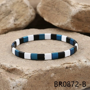 Macro detail of colorful enamel tile stretch bracelet on natural rock surface