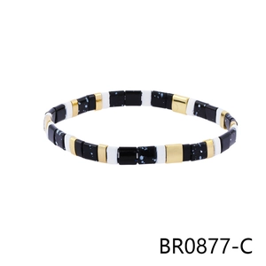 Macro detail of Bohemian geometric beaded bracelet with black and gold textured patterns