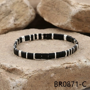 Detail of bohemian black enamel beads and silver spacers on a textured stone base