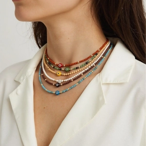 Detailed view of layered bohemian beaded necklaces with blue evil eye charms on a model