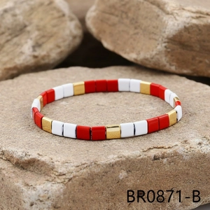Detail view of red, white, and gold Tila bead elastic bracelet on natural stone