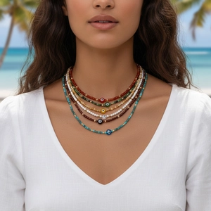 Close-up of colorful Evil Eye beaded necklaces worn by a model on a tropical beach