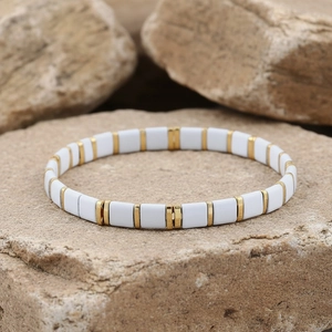 Detail of white Tila beads and gold spacers bracelet placed on a natural stone