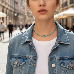 Handmade beaded necklace with blue evil eye pendant and gold accents on a model