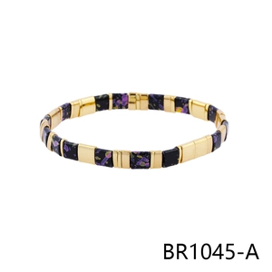 Detail of bohemian black enamel tile bracelet with gold accents and colorful paint splatters