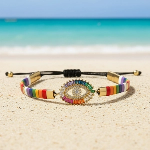 Rainbow Evil Eye bracelet with colorful enamel tiles on beach sand background
