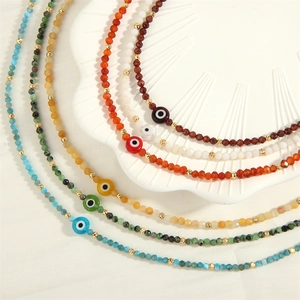 Macro view of colorful faceted glass beads and the evil eye charm on the gold spacers chain