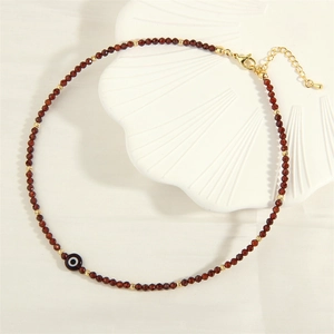 Detail of garnet beaded necklace with evil eye charm and golden adjustable chain
