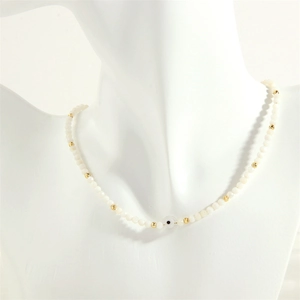 Detail of beaded necklace with white pearls, gold accents and a blue evil eye bead
