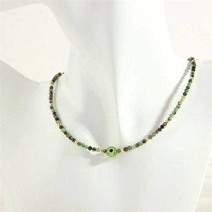 Detail of beaded necklace with evil eye charm and green stones on a neck mannequin
