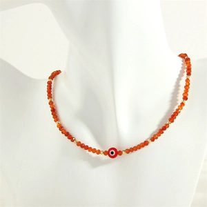 Detail of evil eye charm necklace with orange faceted beads on a mannequin bust