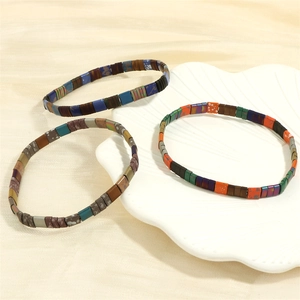 Close-up of bohemian Tila bead stretch bracelets displayed on a white shell plate