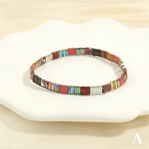 Macro shot of colorful Tila bead elastic bracelet on a white shell plate