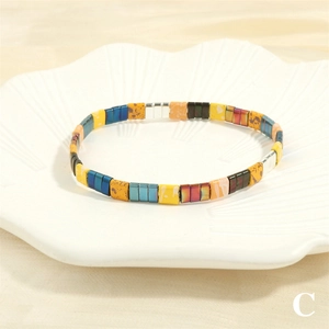 Detailed close-up of colorful Tila bead stretch bracelet on a white shell decorative tray
