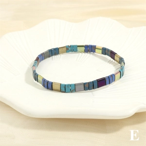 Macro shot of colorful Tila bead stretch bracelet displayed in a white shell dish