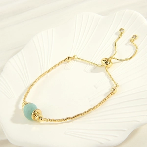Detail von 18K vergoldetem Armband mit verstellbarem Schiebeverschluss und blauem Stein
