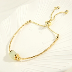 Detail eines 18K vergoldeten Armbands mit grünem Stein und verstellbarem Verschluss