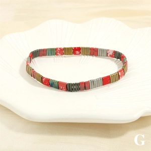 Detail shot of colorful Tila bead bracelet on a white ceramic leaf tray accessory