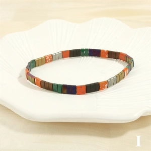 Detail view of Bohemian Tila bead stretch bracelet in a decorative ceramic shell bowl
