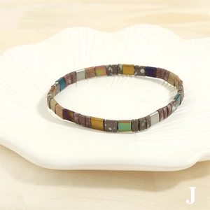 Detailed shot of multi-colored Tila beads bracelet displayed on a shell-shaped ceramic plate