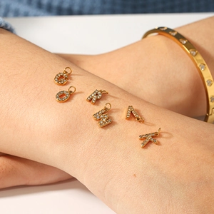 Detailed macro view of 18k gold letter charms with sparkling diamond pavé crystals