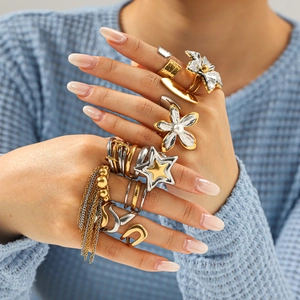 Detail of chunky mixed-metal floral and star rings with pearls and tassels on model