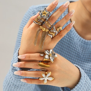 Close-up of statement stainless steel floral rings and star charms on model's fingers