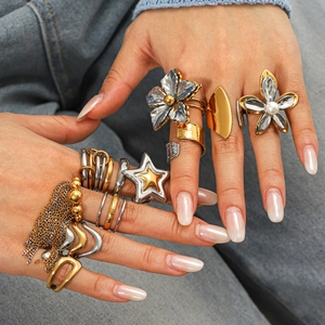 Statement two-tone stainless steel ring set with flower and pearl designs on denim